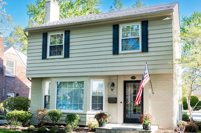 view of front facade featuring a chimney and brick siding