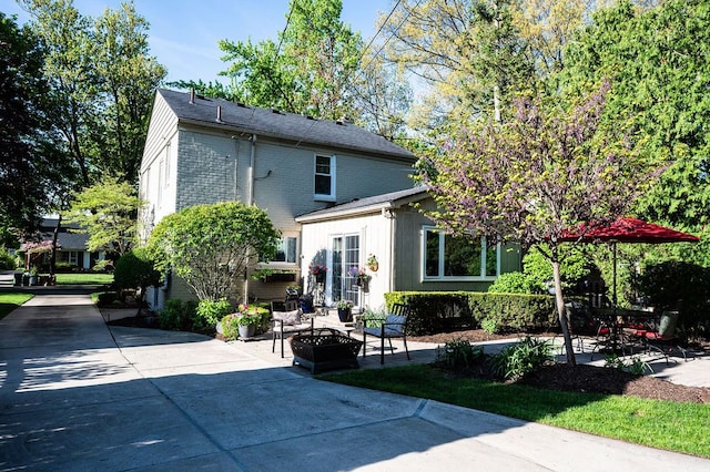 view of front of property with a patio, an outdoor fire pit, and brick siding