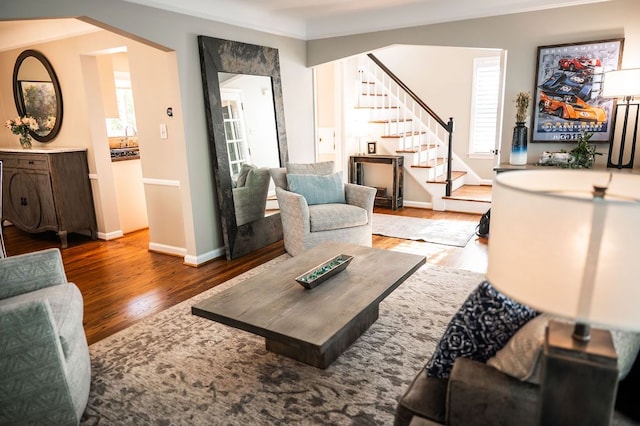 living area featuring wood finished floors, stairway, plenty of natural light, crown molding, and baseboards