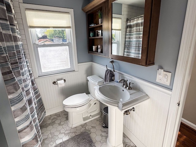 full bathroom with a wainscoted wall, toilet, a shower with shower curtain, and tile patterned floors