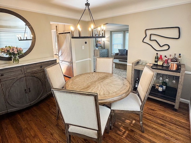 dining space featuring arched walkways, a chandelier, dark wood-type flooring, ornamental molding, and a bar