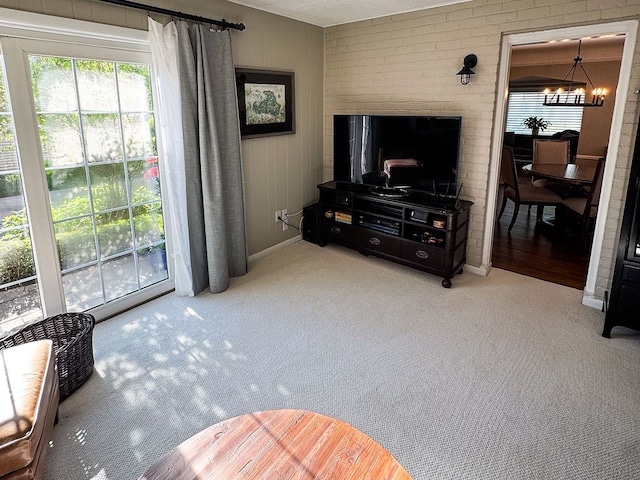 carpeted living area with a chandelier and baseboards