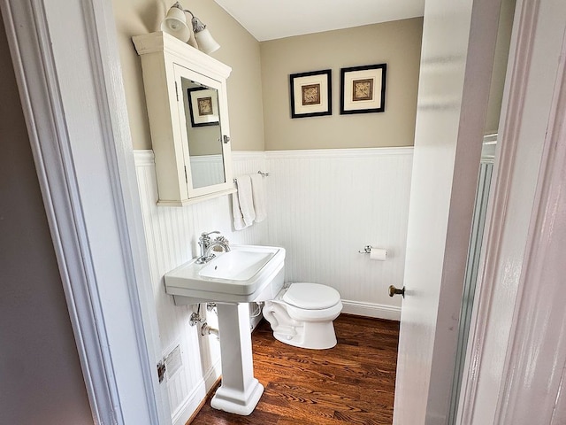 half bathroom featuring wainscoting, toilet, and wood finished floors