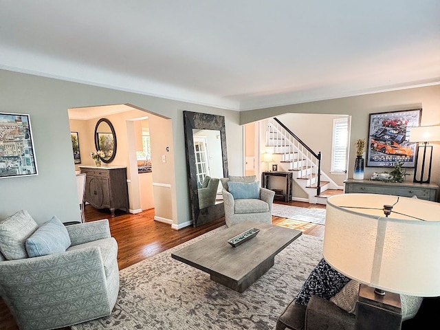 living room featuring crown molding, stairway, wood finished floors, healthy amount of natural light, and arched walkways