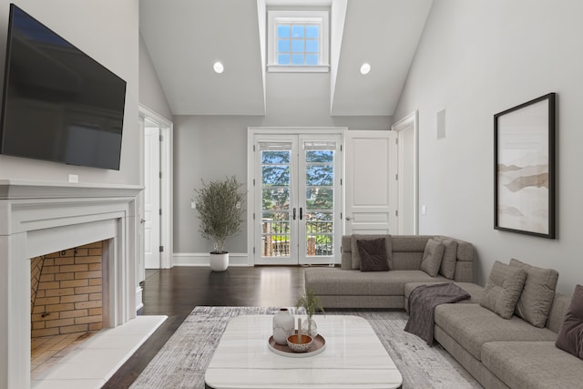living room with high vaulted ceiling, french doors, wood finished floors, a fireplace with raised hearth, and baseboards