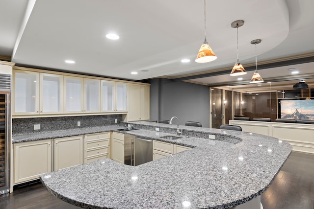 kitchen featuring a sink, stainless steel dishwasher, cream cabinets, a peninsula, and dark wood-style floors