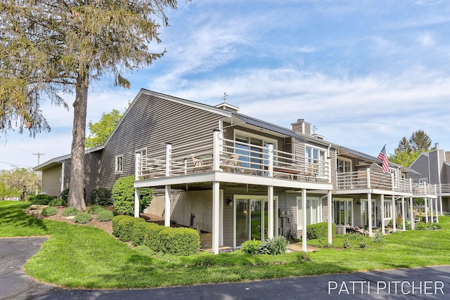 618 Edgewater Dr, Spring Lake, MI 49456 - back of house with a chimney, a deck, and a lawn
