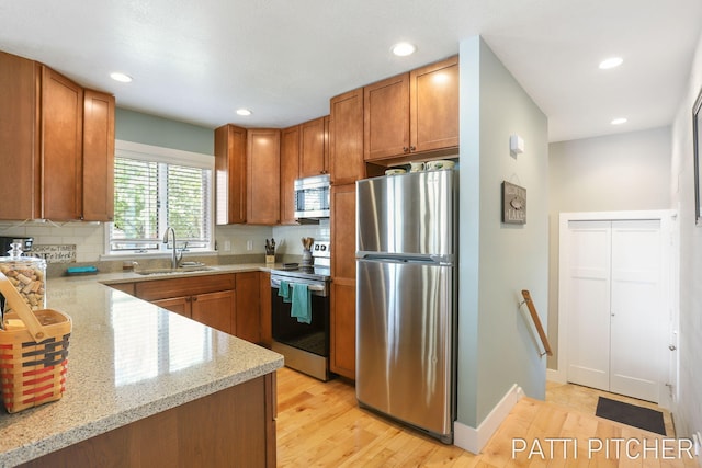 618 Edgewater Dr, Spring Lake, MI 49456 - kitchen featuring appliances with stainless steel finishes, a sink, light stone counters, light wood-type flooring, and recessed lighting