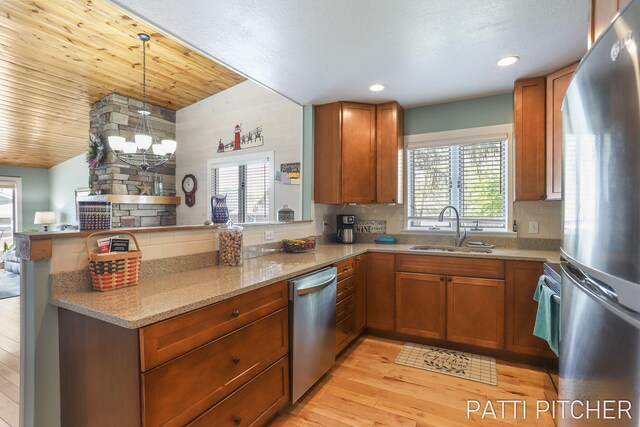 618 Edgewater Dr, Spring Lake, MI 49456 - kitchen with stainless steel appliances, a sink, a peninsula, light stone counters, and light wood-style flooring