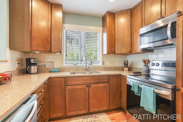 618 Edgewater Dr, Spring Lake, MI 49456 - kitchen with appliances with stainless steel finishes, a sink, brown cabinets, and tasteful backsplash
