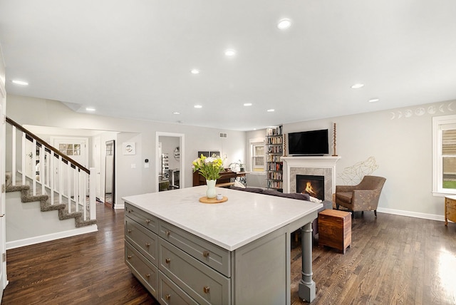 kitchen featuring gray cabinetry, dark wood finished floors, a center island, a fireplace, and recessed lighting
