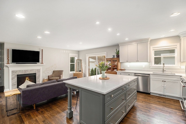 kitchen featuring stainless steel dishwasher, a sink, gray cabinetry, white cabinetry, and a center island