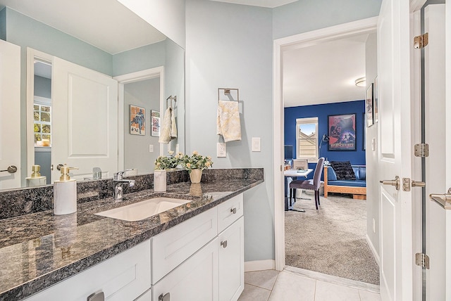 ensuite bathroom with baseboards, healthy amount of natural light, vanity, and tile patterned floors