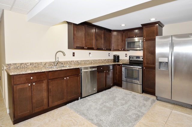 18516 Ranier Dr, Macomb, MI 48042 - kitchen with stainless steel appliances, a sink, light tile patterned floors, light stone countertops, and dark brown cabinets