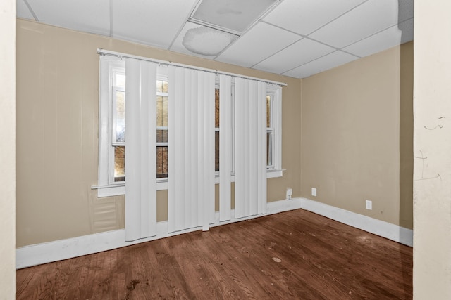 empty room featuring wood finished floors, baseboards, and a drop ceiling