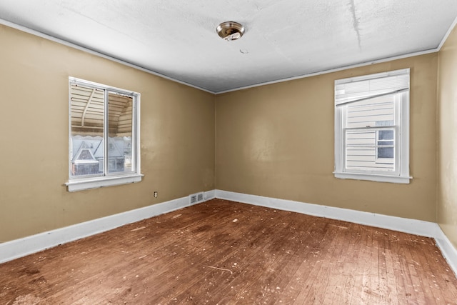 spare room with hardwood / wood-style floors, baseboards, and crown molding