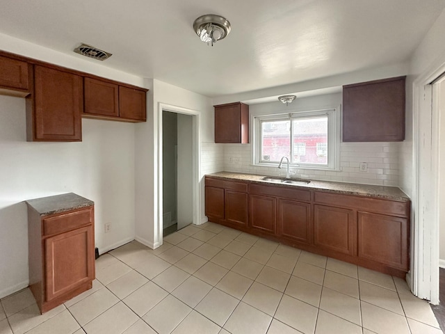 17124 Pinehurst St, Detroit, MI 48221 - kitchen featuring a sink, tasteful backsplash, brown cabinets, light tile patterned floors, and stone counters