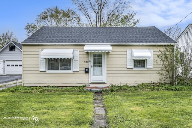 view of front of home with an outdoor structure, a front lawn, a garage, and a shingled roof