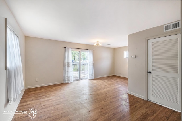 spare room with plenty of natural light, wood finished floors, and baseboards