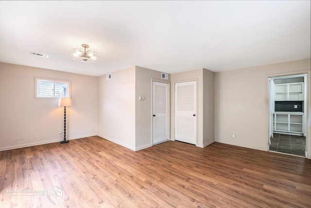 spare room with light wood-style flooring, a chandelier, and baseboards