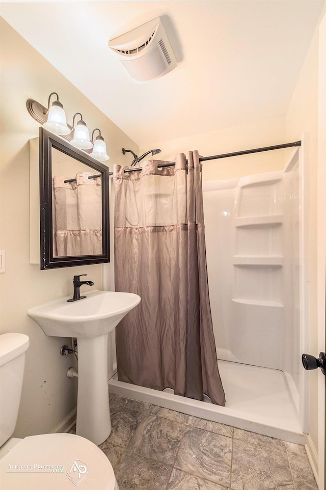 full bath with toilet, a shower stall, and baseboards