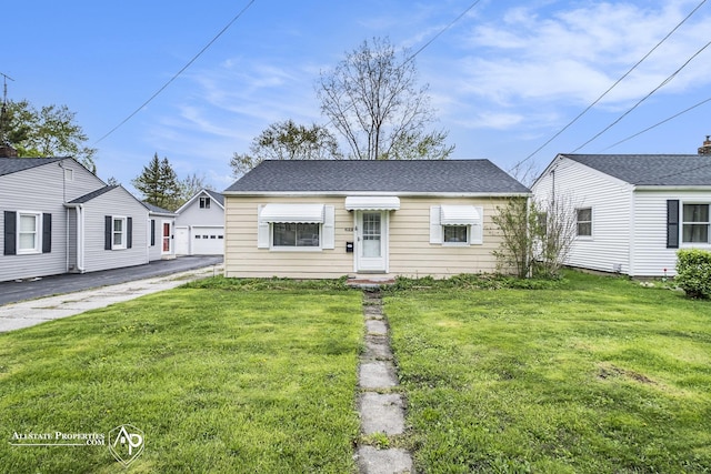 view of front facade featuring a front lawn, an outdoor structure, and asphalt driveway