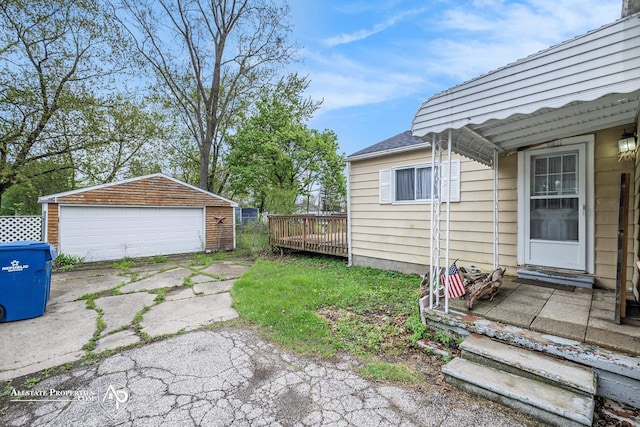 view of yard with a garage, an outbuilding, and a wooden deck