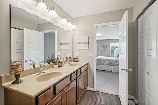 7051 Wildflower, Grand Blanc, MI 48439 - bathroom featuring double vanity, connected bathroom, a closet, baseboards, and wood finished floors