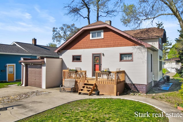 view of front of home featuring concrete driveway, a deck, a chimney, a front yard, and an attached garage