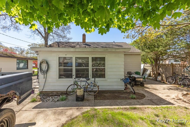 back of property with fence, a chimney, and a patio