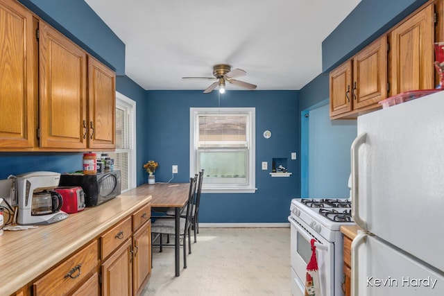 kitchen featuring white appliances, light countertops, a ceiling fan, brown cabinetry, and baseboards