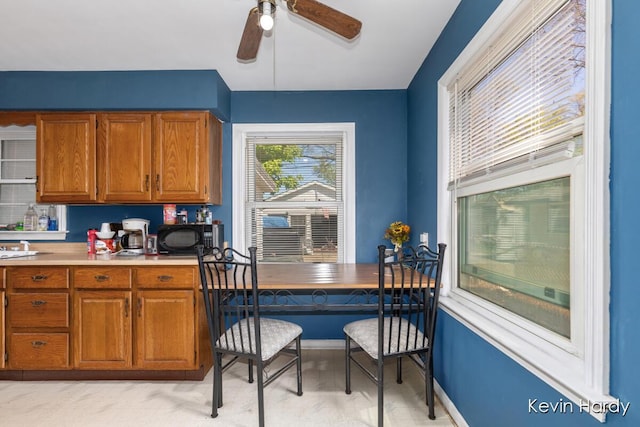 kitchen featuring black microwave, brown cabinets, a ceiling fan, and light countertops