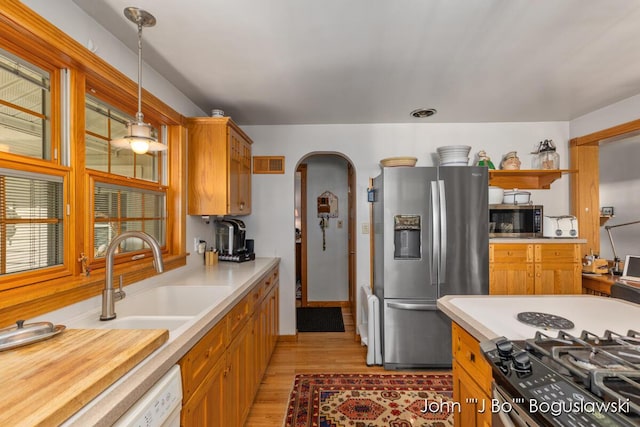 1017 Pearl St, Belding, MI 48809 - kitchen featuring appliances with stainless steel finishes, a sink, light countertops, light wood-type flooring, and arched walkways
