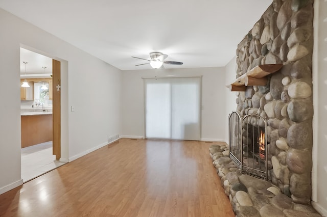 1699 Brentwood Dr, Wixom, MI 48393 - unfurnished living room featuring a fireplace, a ceiling fan, light wood-type flooring, a sink, and baseboards