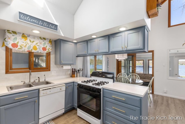 7964 W Royal Rd, Stanwood, MI 49346 - kitchen featuring gas range oven, white dishwasher, a sink, a peninsula, and light wood-style flooring