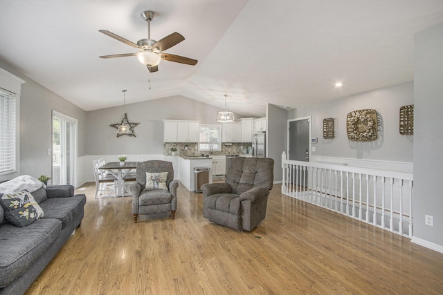 living area featuring vaulted ceiling, a ceiling fan, and light wood-style flooring