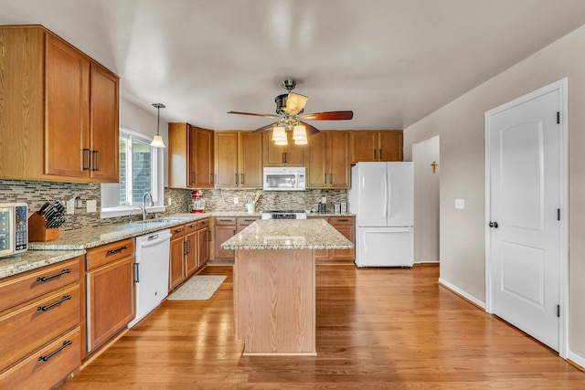 kitchen featuring white appliances, light wood-type flooring, a sink, and backsplash