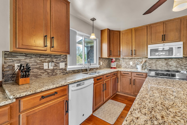 kitchen featuring white appliances, a sink, dark wood-style floors, tasteful backsplash, and brown cabinets