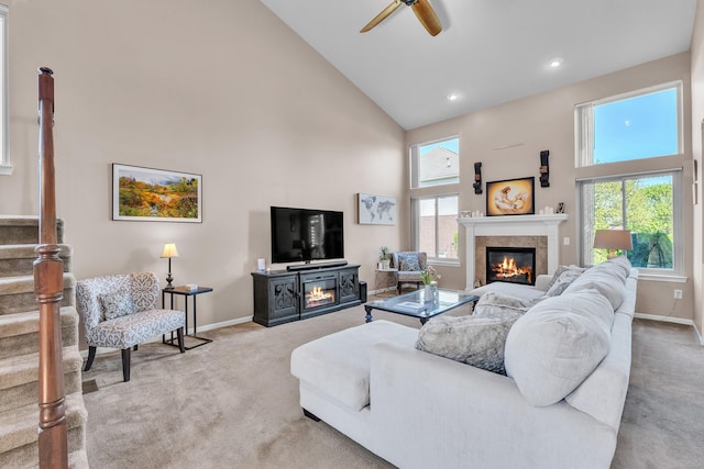 living room with a glass covered fireplace, high vaulted ceiling, carpet floors, baseboards, and a ceiling fan
