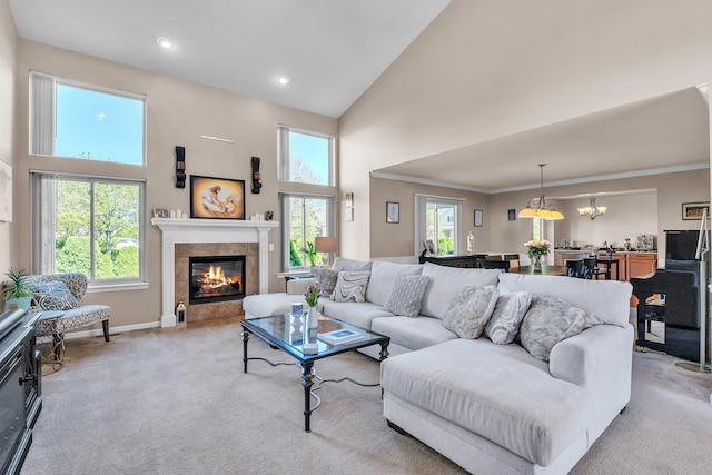 living area with high vaulted ceiling, light carpet, a tiled fireplace, baseboards, and a chandelier