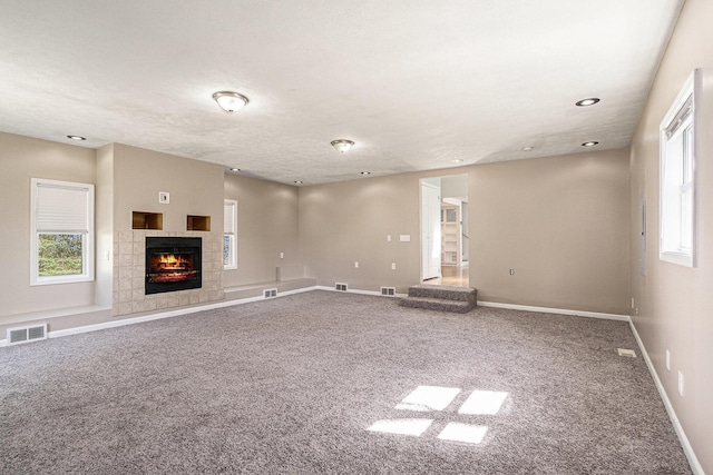 unfurnished living room with carpet, plenty of natural light, a tile fireplace, and recessed lighting