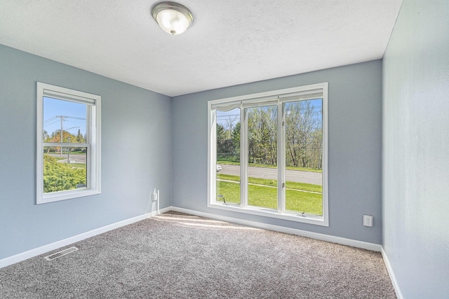 carpeted empty room featuring baseboards and a textured ceiling