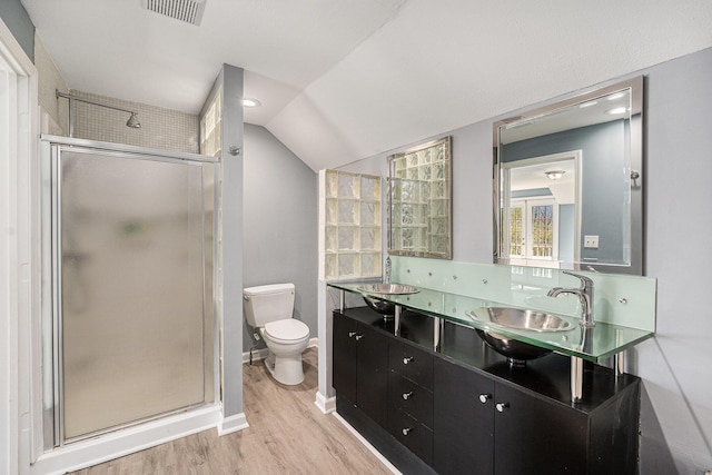 full bath with a shower stall, wood finished floors, toilet, vaulted ceiling, and double vanity