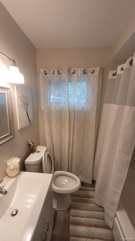 606 E Milton Ave, Hazel Park, MI 48030 - bathroom featuring curtained shower, toilet, vanity, and wood finished floors