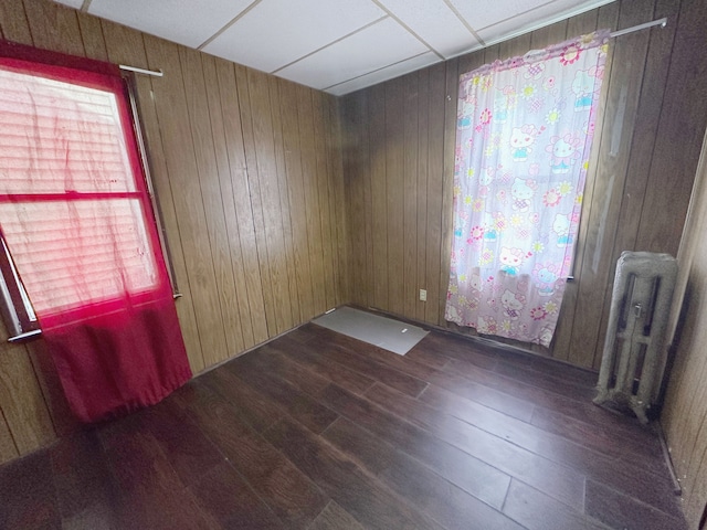 spare room with wood finished floors, radiator heating unit, and wooden walls