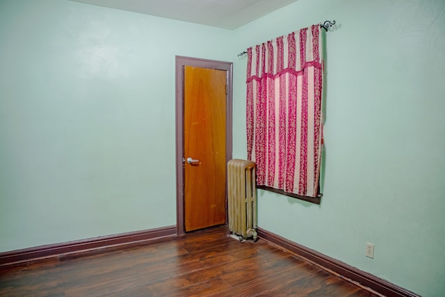 empty room with radiator, baseboards, and wood finished floors