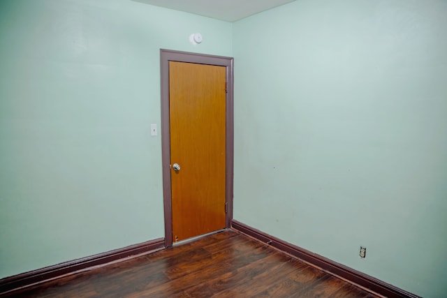 spare room featuring baseboards and dark wood finished floors