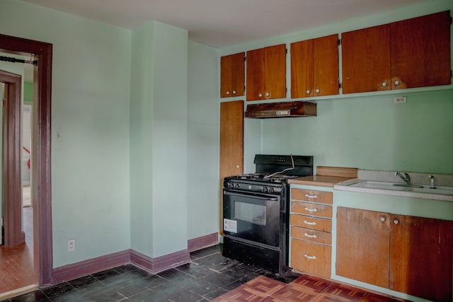 kitchen featuring black gas stove, under cabinet range hood, a sink, light countertops, and brown cabinets