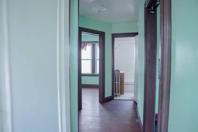 corridor featuring dark wood-style flooring and baseboards