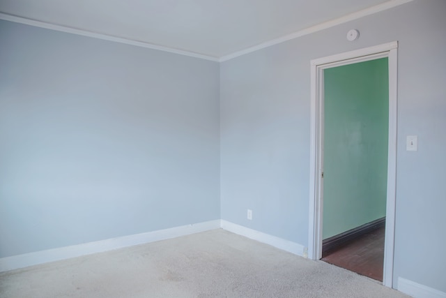 carpeted empty room with crown molding, baseboards, and a smoke detector
